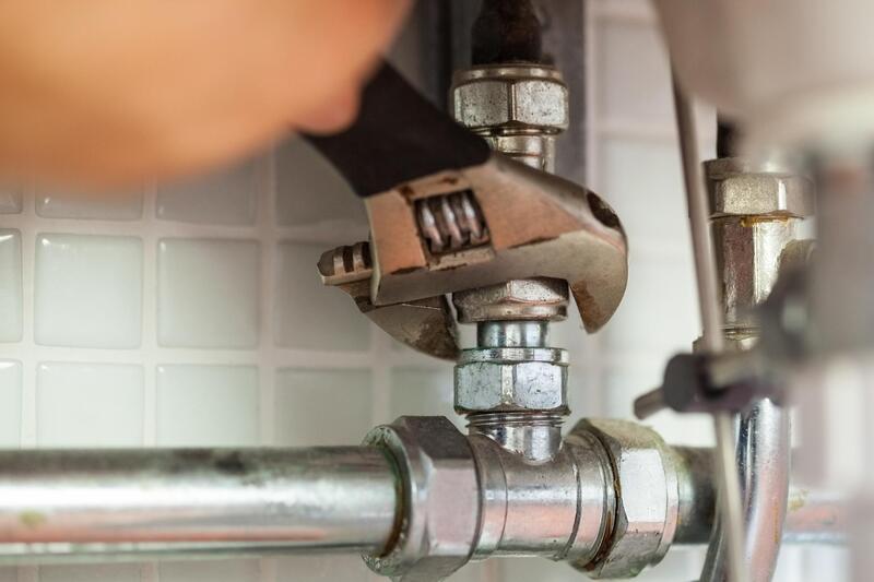 a wrench being used to tighten up a feed line to a sink