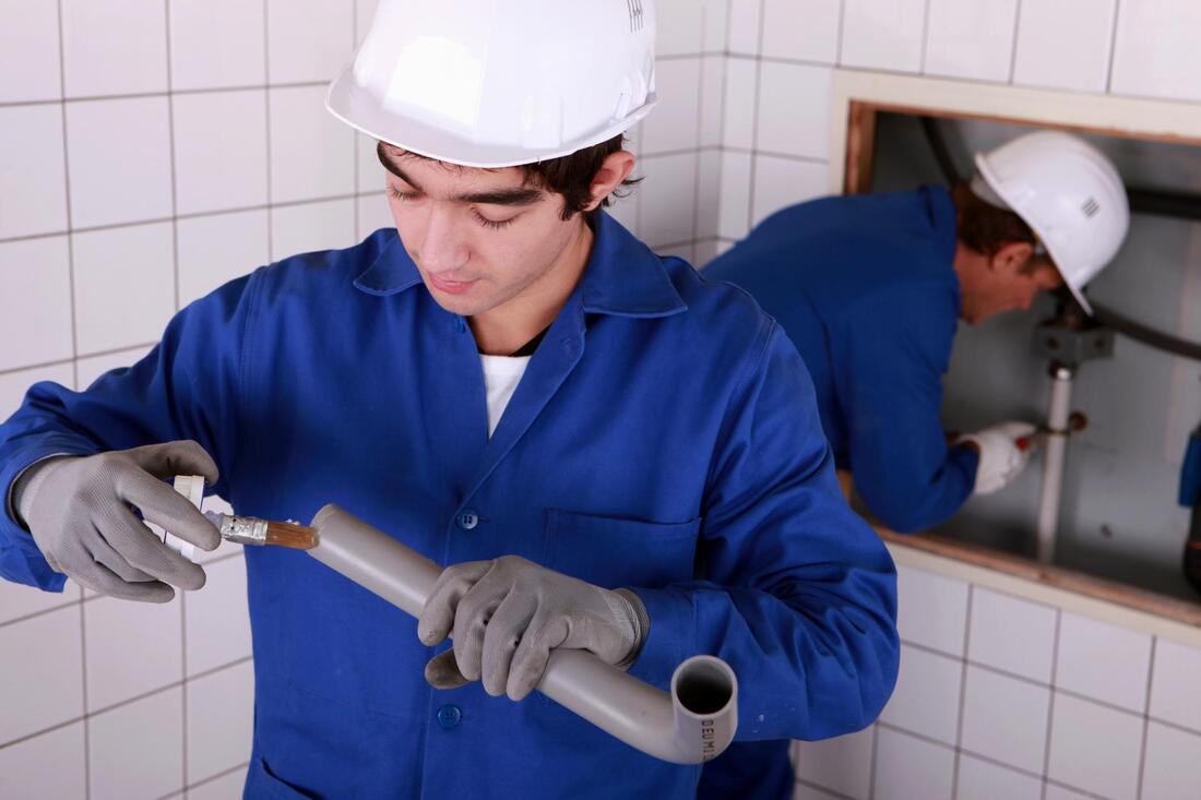two plumbers working on detecting a fixing a leak