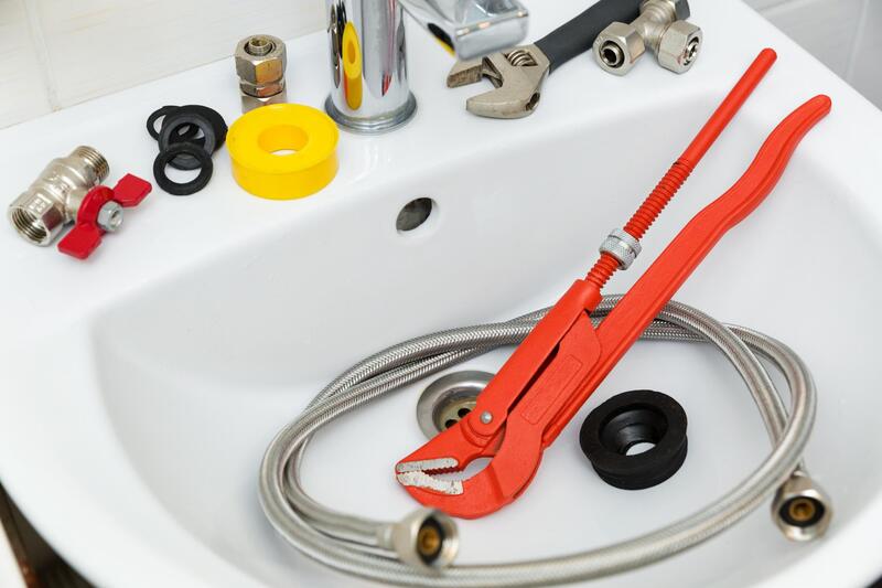 a sink with plumbing tools being laid out to work on a residential sink