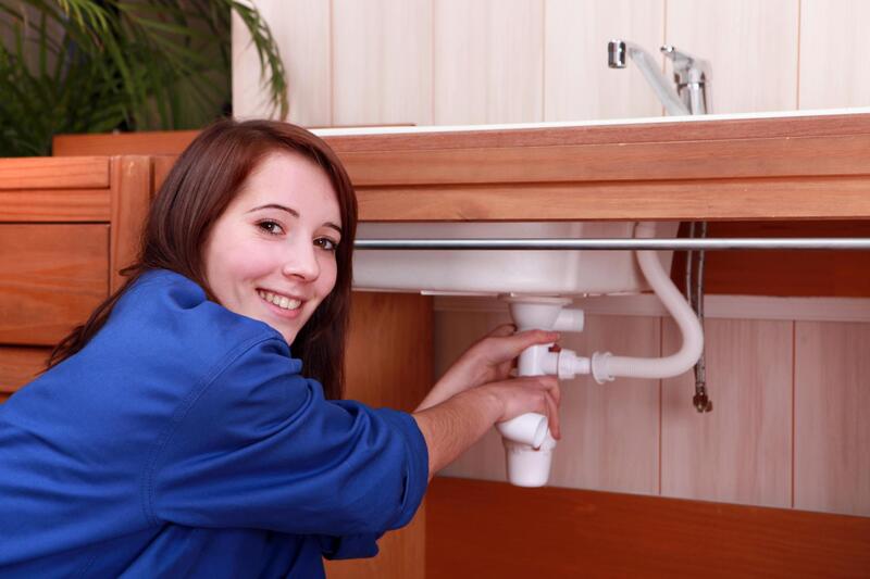a happy plumber working on a sink drain in a residential plumbing job