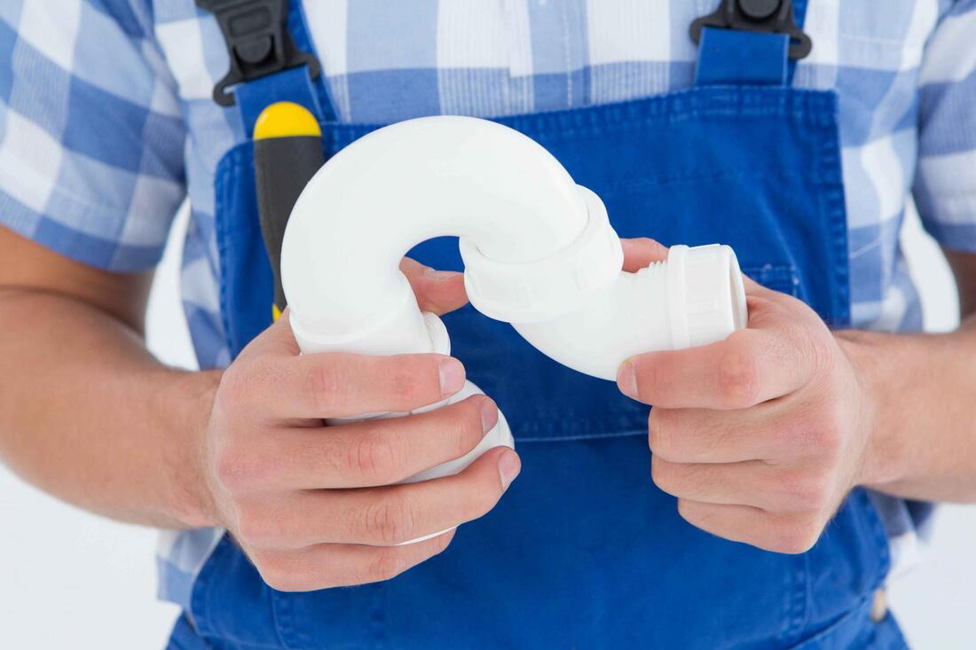 a plumber holding a pvc sink j trap for commercial plumbing