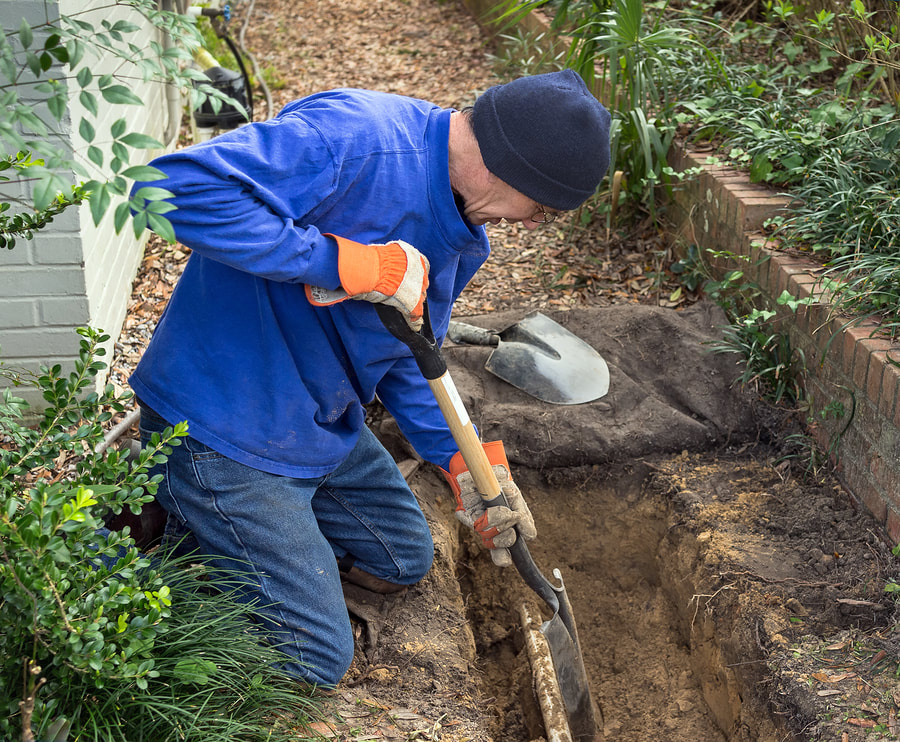 a plumber digging a trench for purposes of burying a drain line